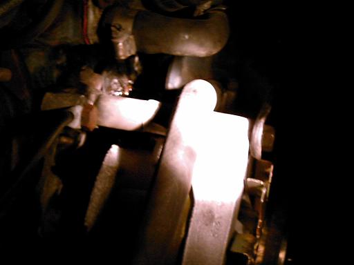 Close-up of engine parts with hoses and metal components visible in darkness