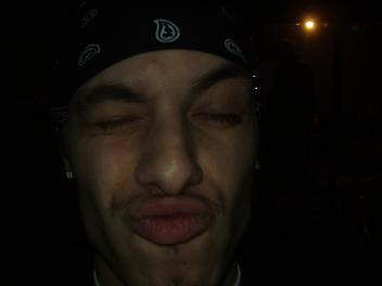 1994 Ford Taurus - A person wearing a bandana makes a kissing face in this dimly lit photo, with the Supermotors logo in the corner.