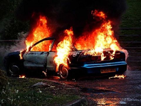 1996 Ford Probe - A blue 1996 Ford Probe is consumed by fire on a roadside.