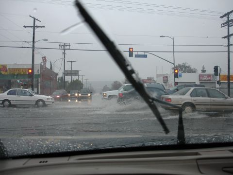 1993 Ford Taurus - Multiple vehicles navigate a flooded intersection during heavy rain.