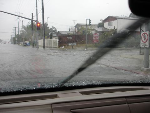 1993 Ford Taurus - Navigating through a flooded intersection during heavy rain, with traffic signals and street signs visible.