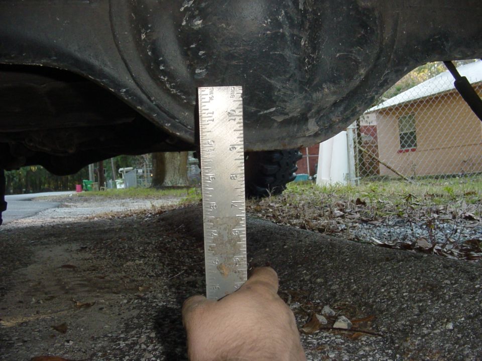 Ruler measuring rear axle clearance on a vehicle
