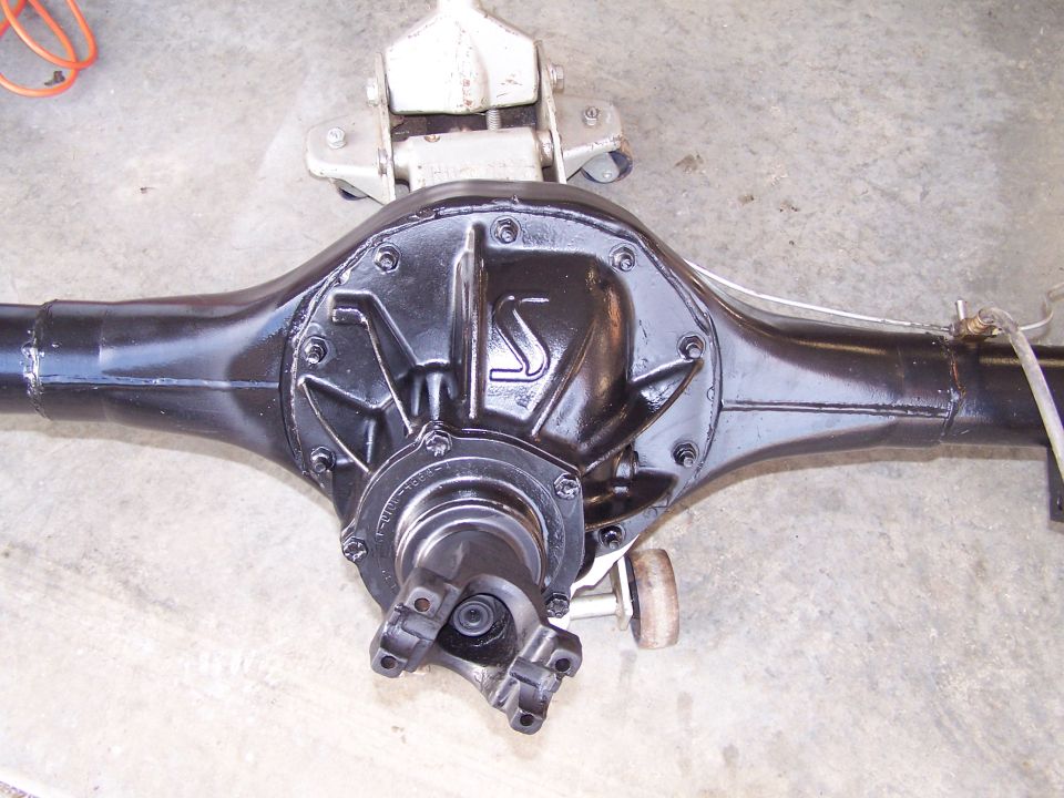 Black rear axle assembly with a "S" logo on the differential cover, resting on a jack