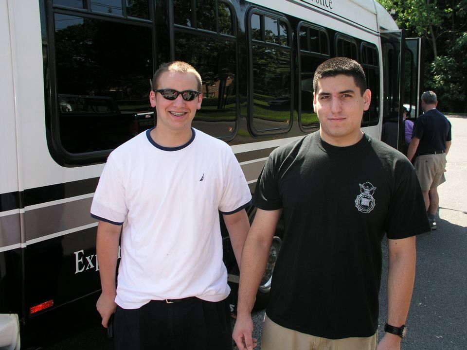 Side view of a white and black bus with two men standing in front