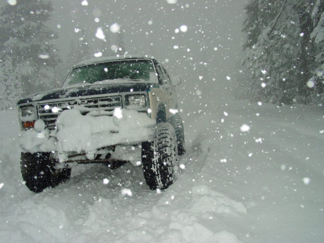 1986 Ford Bronco driving through heavy snow, front view