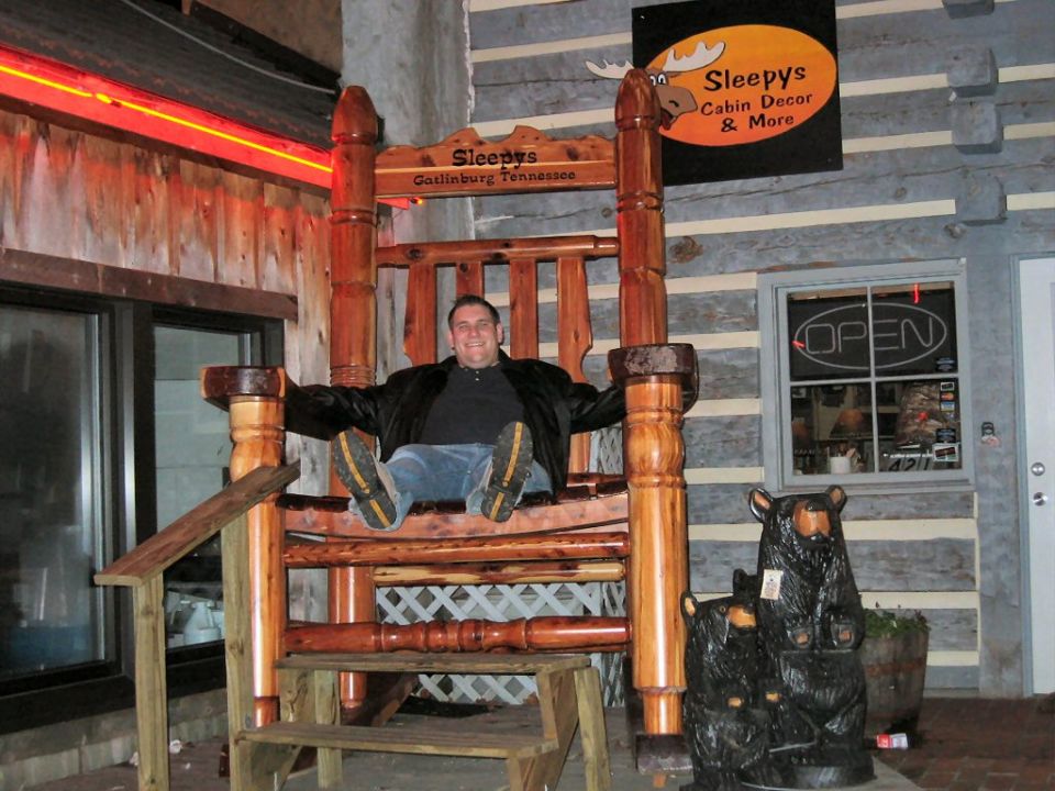Man in giant rocking chair outside Sleepy's Cabin Decor, Gatlinburg, Tennessee