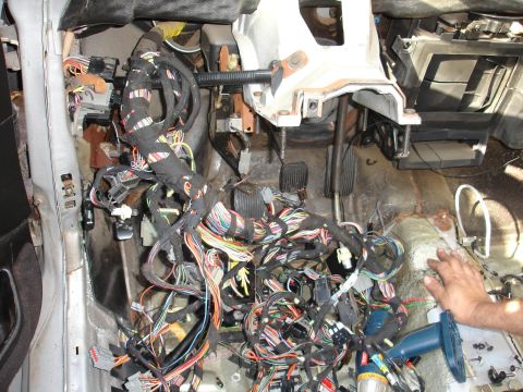 1993 Ford Taurus - A car's interior is disassembled, revealing a tangled mess of wires and the brake and accelerator pedals.