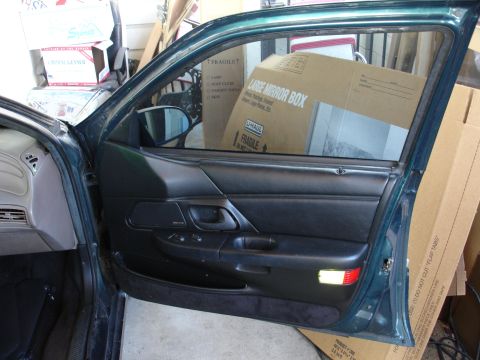 1993 Ford Taurus - Interior view of a car door, showing the panel and a reflection of boxes in the window.