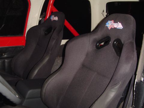 1989 Jeep YJ - Interior view of a vehicle showing two aftermarket racing seats with an American flag emblem.