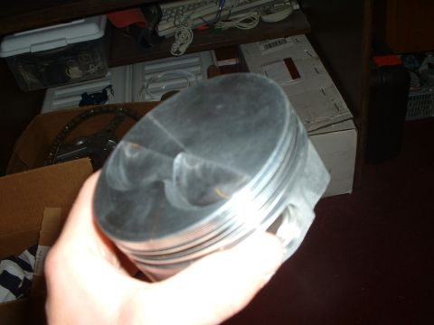 1985 Ford Bronco - Engine piston held in hand, showing valve reliefs and ring grooves.