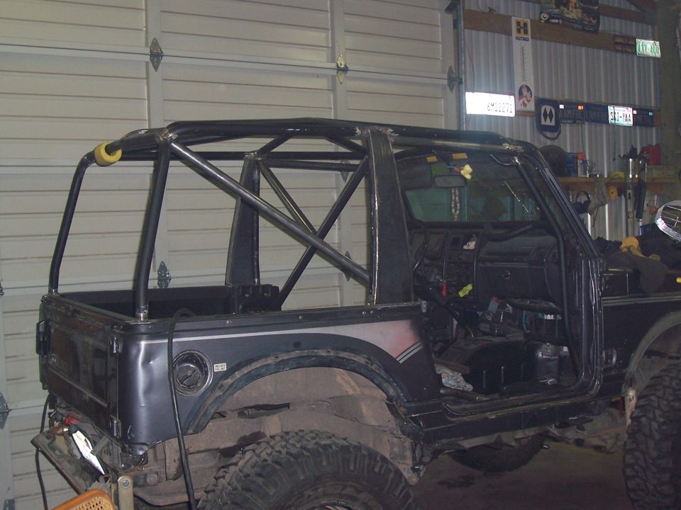 Suzuki Samurai with custom roll cage installed, doors removed, in a garage
