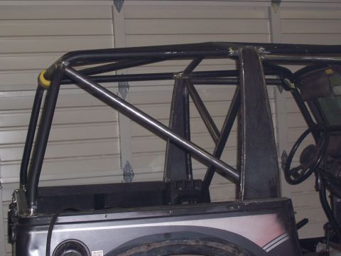 1988 Suzuki Samurai - A custom roll cage is installed on the rear of a silver vehicle, viewed from a high angle inside a garage.