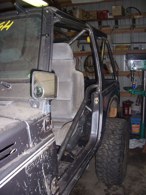 1988 Suzuki Samurai - A Suzuki Samurai is shown with a custom roll cage and off-road tires, parked inside a garage.