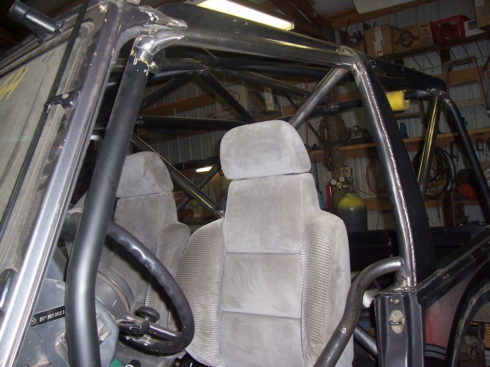 interior of off-road vehicle with roll cage, bucket seats, and steering wheel