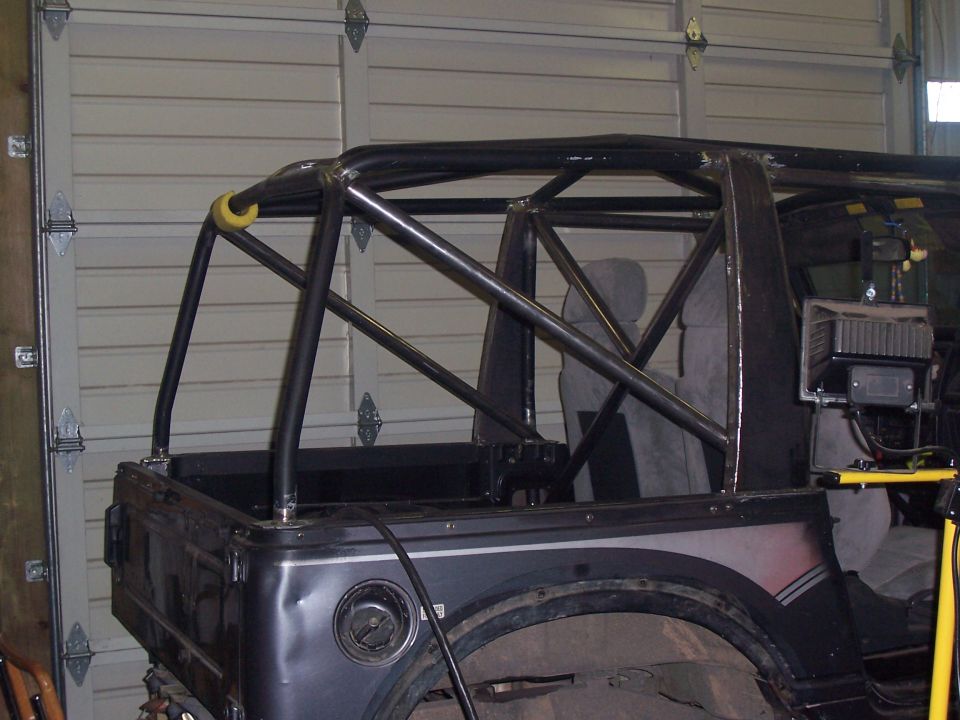 1988 Suzuki Samurai rear quarter view with custom roll cage, dark gray body, and SuperMotors logo