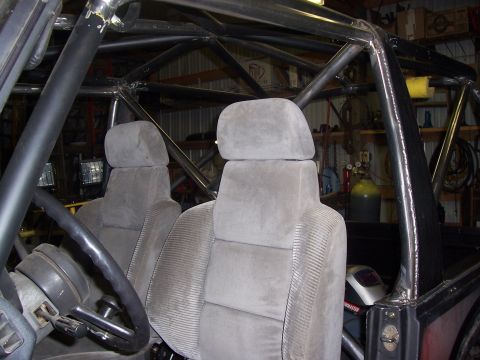 1988 Suzuki Samurai - Vehicle interior with extensive custom roll cage structure and grey seats.