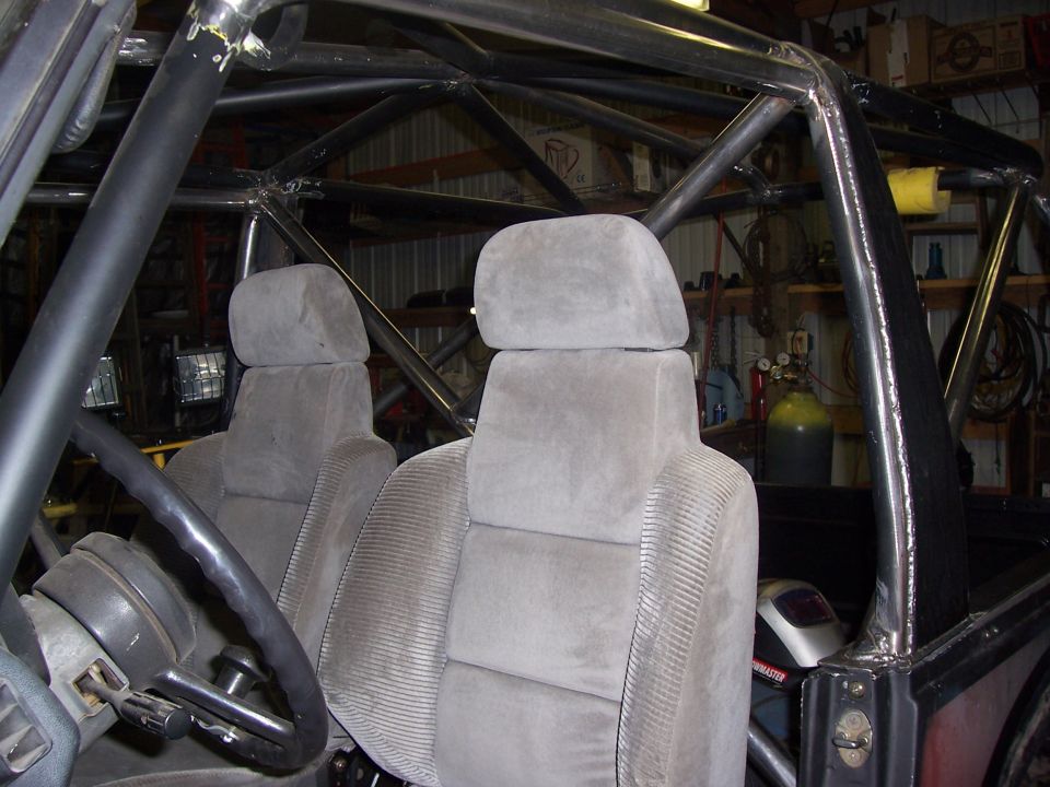 Interior of a vehicle with a custom roll cage and grey fabric seats
