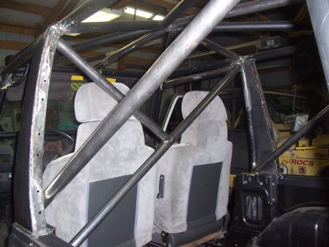 1988 Suzuki Samurai - The interior of a vehicle shows a custom-built roll cage structure surrounding the front seats.