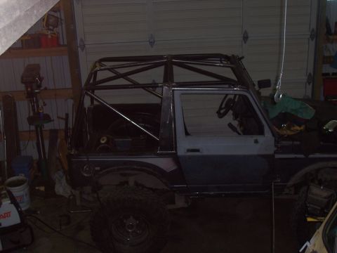 1988 Suzuki Samurai - This vehicle is undergoing modifications, a newly installed roll cage in a workshop setting.