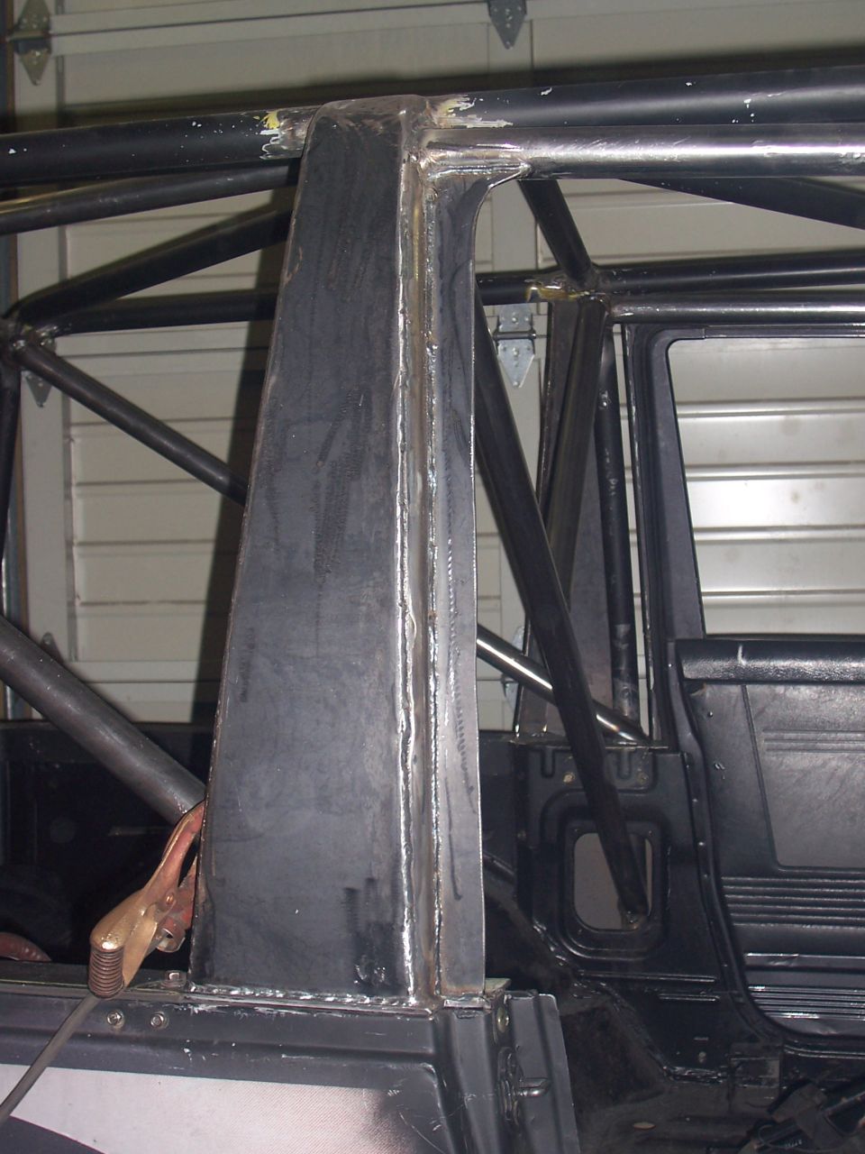 Roll cage structure welded to vehicle interior, showing metal fabrication