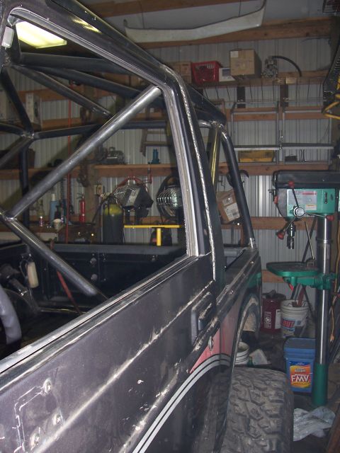 1988 Suzuki Samurai - This Suzuki Samurai is undergoing modifications, a newly installed roll cage inside a workshop.