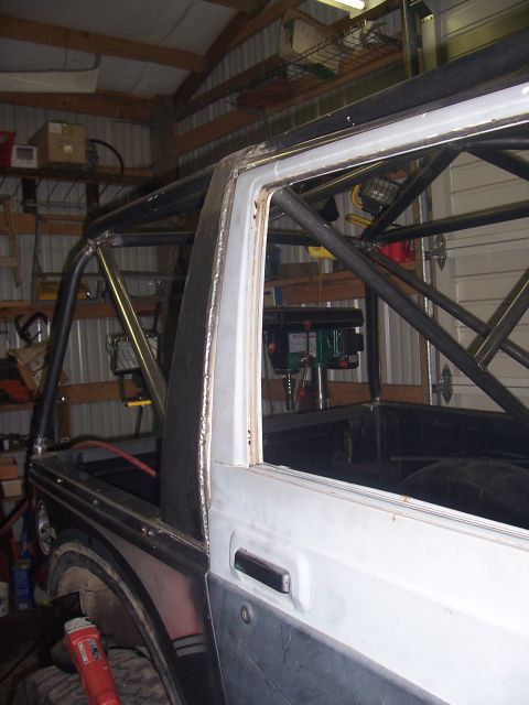 1988 Suzuki Samurai - A Suzuki Samurai is undergoing modifications with a custom roll cage being installed in a workshop.