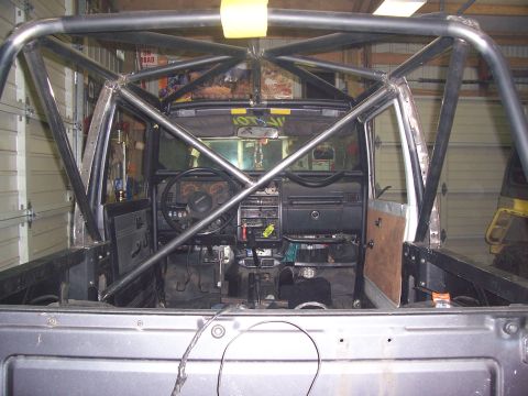 1988 Suzuki Samurai - The interior of a vehicle is visible, a custom-installed roll cage and a dashboard with various controls.