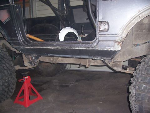 1988 Suzuki Samurai - The underside of a vehicle is shown with a red jack stand supporting the frame during repairs.