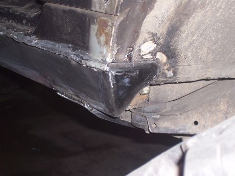 1988 Suzuki Samurai - Close-up view of a vehicle's undercarriage, showing areas of rust and newly welded metal on the rocker panel.