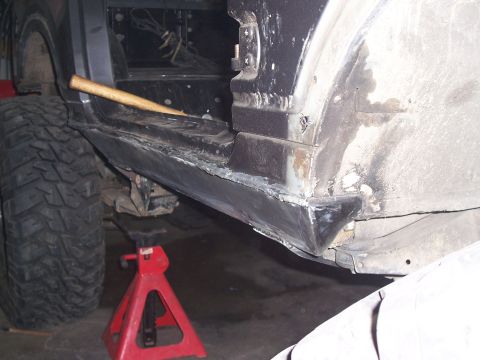 1988 Suzuki Samurai - Close-up view of rocker panel repair work on a vehicle, with a large tire visible.