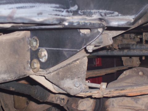 1988 Suzuki Samurai - Close-up view of a vehicle's undercarriage, showing suspension components and bolted metal brackets.