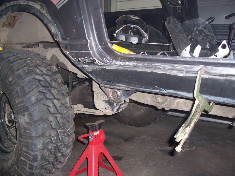 1988 Suzuki Samurai rocker panel rust repair, showing large off-road tire and jack stand