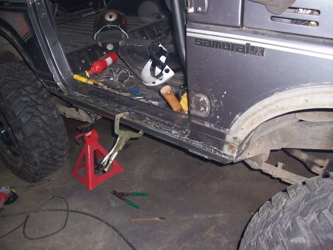 1988 Suzuki Samurai - Gray Suzuki Samurai JX shows modifications with a roll cage and large tires, with tools scattered around.