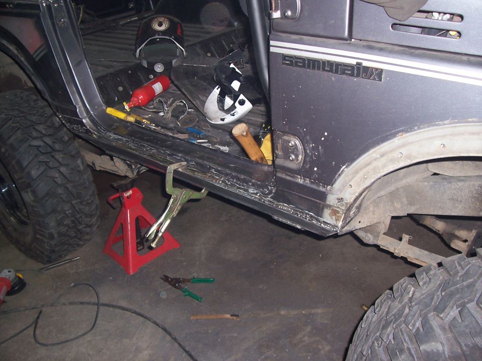 Gray Suzuki Samurai JX with custom roll cage, large tires, and tools on the floor