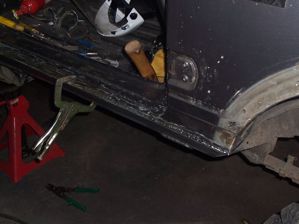 Dark gray vehicle rocker panel repair with welding and clamps