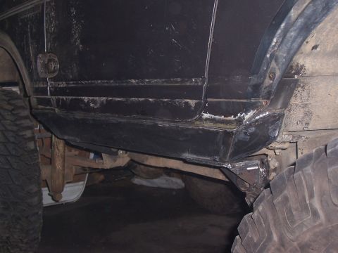 1988 Suzuki Samurai - Custom rock sliders have been welded onto the side of this black off-road vehicle.