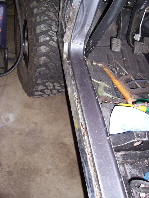 1988 Suzuki Samurai - Interior view of a vehicle with tools and a large tire, showing a rusty door sill.
