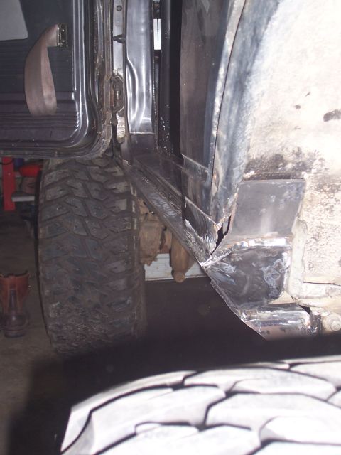 1988 Suzuki Samurai - Close-up view of a heavily modified rocker panel and a large off-road tire on a vehicle.