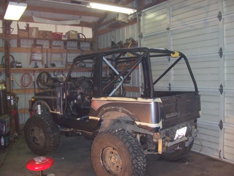 1988 Suzuki Samurai - Suzuki Samurai in garage, modified with a roll cage and off-road tires.
