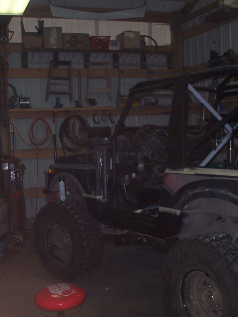 1988 Suzuki Samurai - Modified 1988 Suzuki Samurai with custom roll cage and off-road tires sits in a garage.