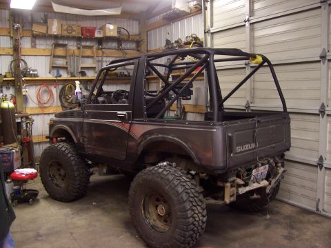 1988 Suzuki Samurai - Modified 1988 Suzuki Samurai in a garage, a full roll cage and off-road tires.