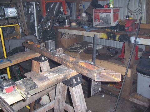 1988 Suzuki Samurai - A fabricated metal frame is supported by sawhorses in a cluttered workshop environment.