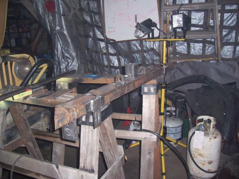 1988 Suzuki Samurai - A metal frame assembly is being worked on in a workshop setting, with tools and equipment visible in the background.
