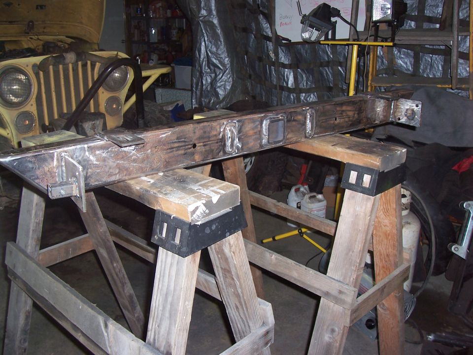 Metal frame on sawhorses in a garage, with a yellow vehicle in the background