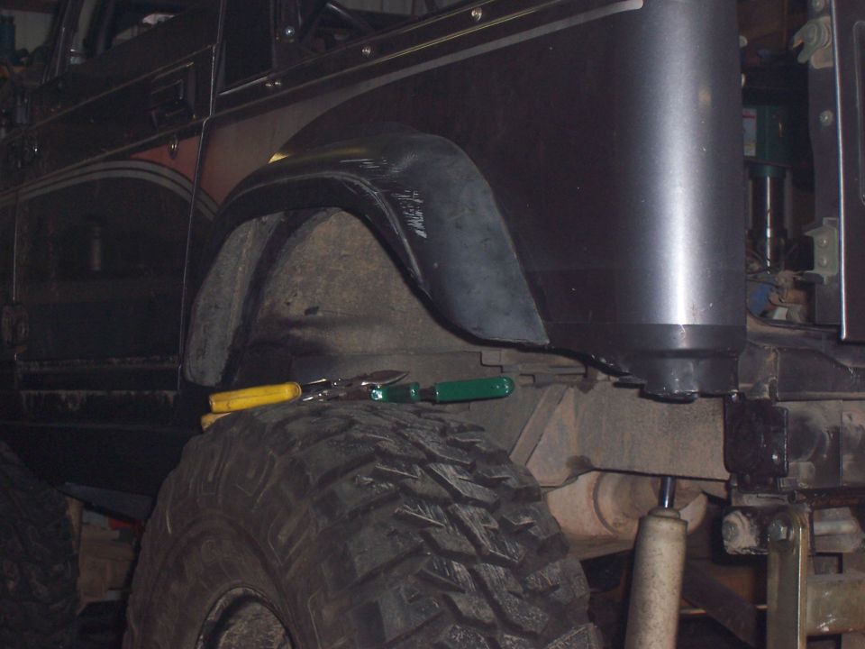 Dark off-road vehicle fender and large tire with tools on top