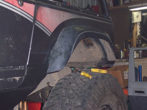 1988 Suzuki Samurai - Detail of a vehicle's fender and tire, showing the wheel well area.