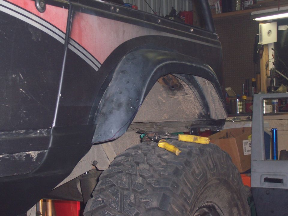 Close-up of a vehicle's rear fender well and tire, with tools on the tire