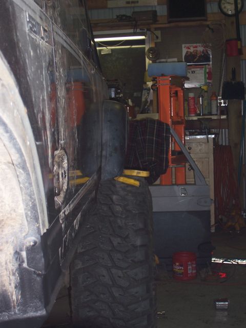 1988 Suzuki Samurai - A vehicle's side panel and large tire are visible in a cluttered garage setting.