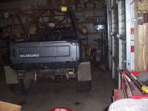 1988 Suzuki Samurai - This Suzuki Samurai, seen from the rear, features a prominent roll cage and "SUZUKI" branding on its tailgate.