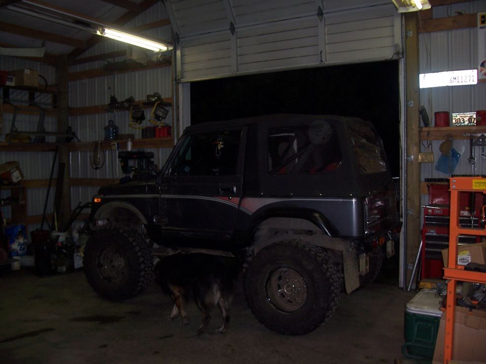 Dark SUV with large tires and soft top in garage